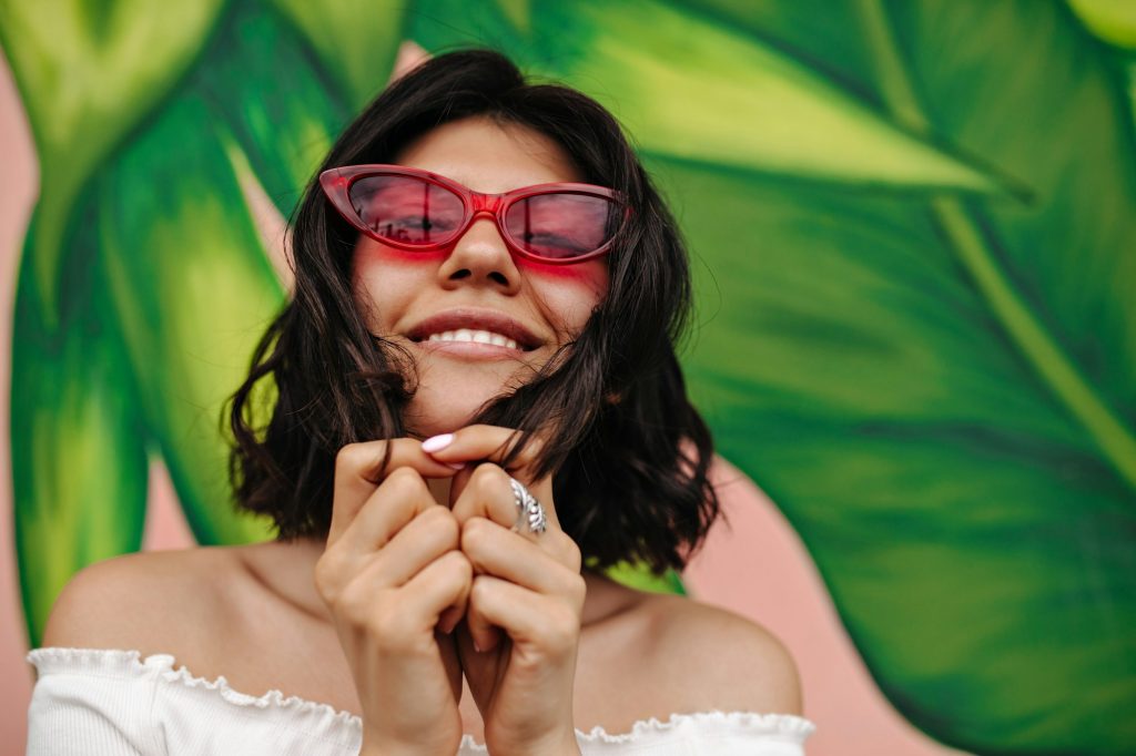 Carefree female model posing near graffiti. Front view of sensual girl in pink sunglasses.