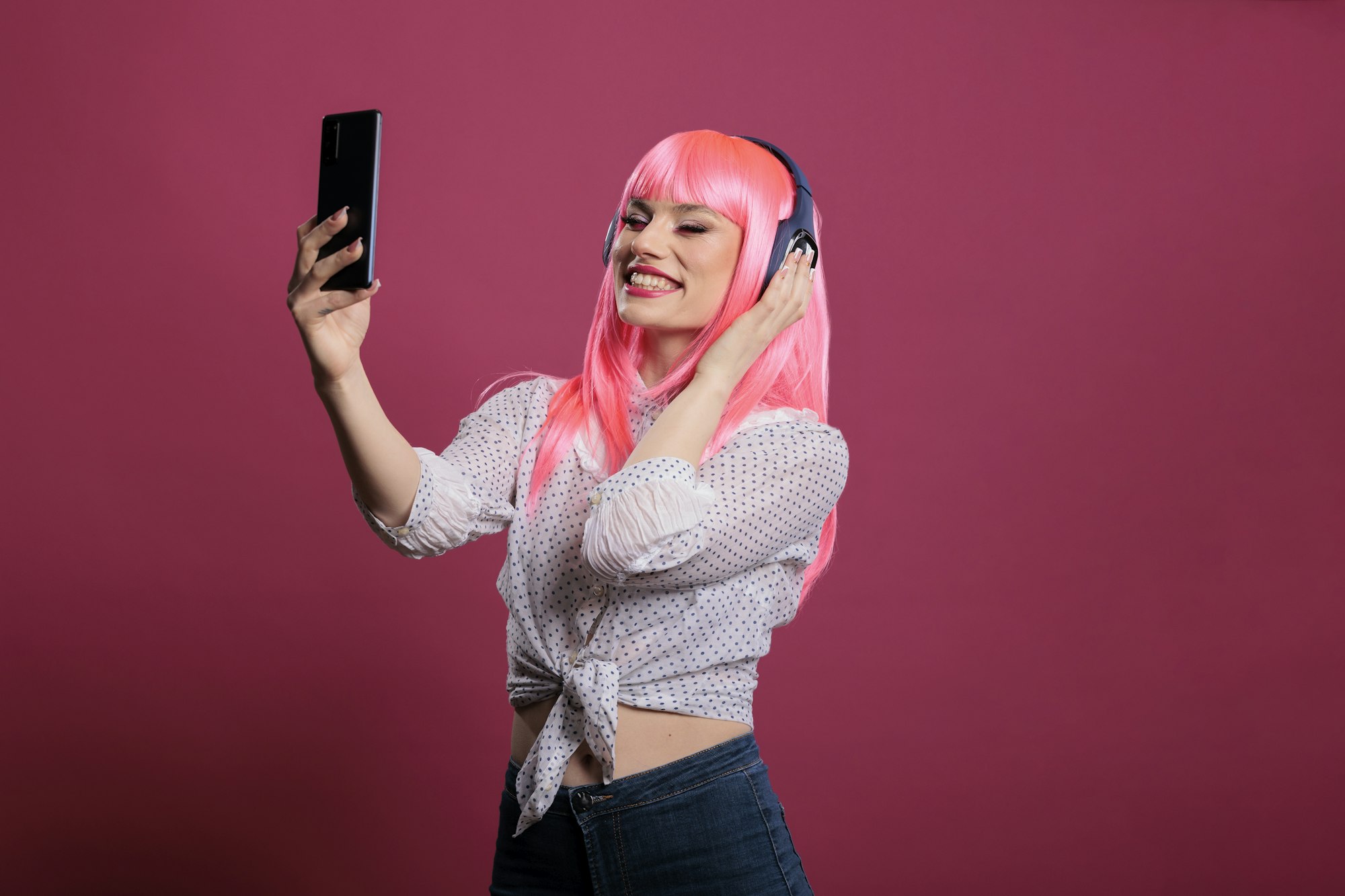 Female model with pink hair taking pictures or recording video