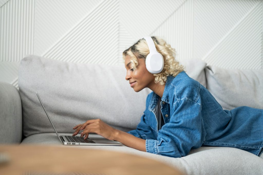 Young freelancer working at home lying on the couch. Student girl watching lecture etc. Remote job,e